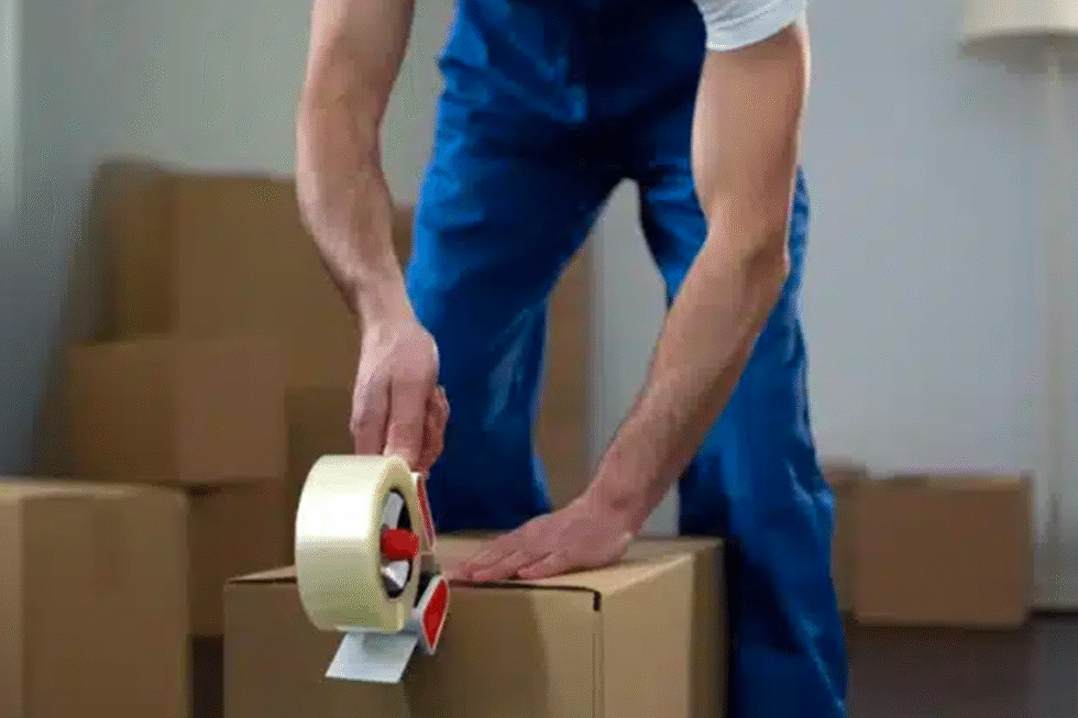 Un déménageur de l'entreprise Transport Five Star en train d'emballer un carton lors d'un déménagement.