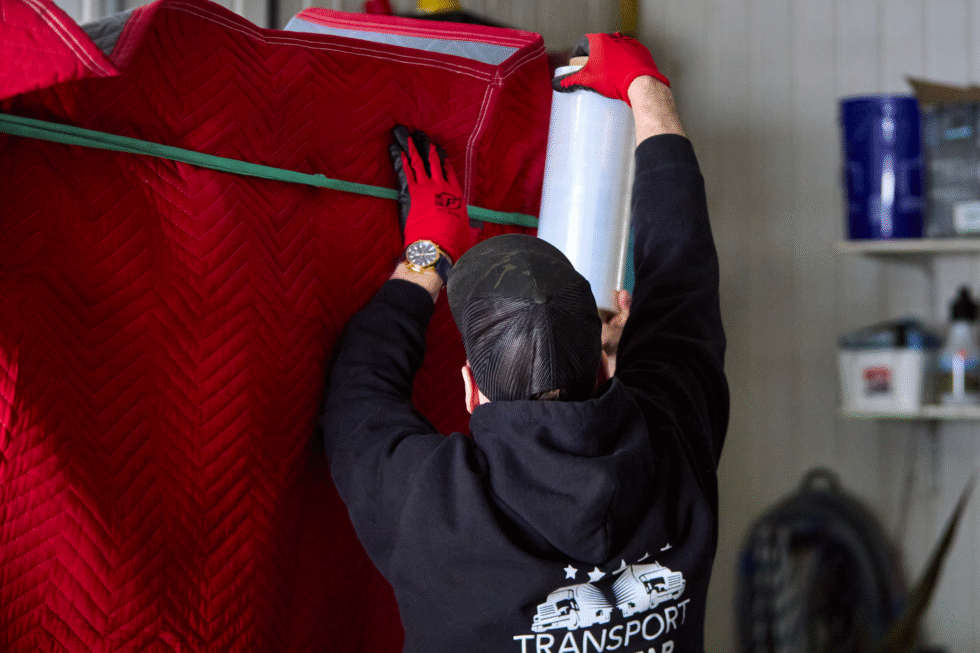 Un de nos déménageur, vu de dos, en train d'emballer un meuble.