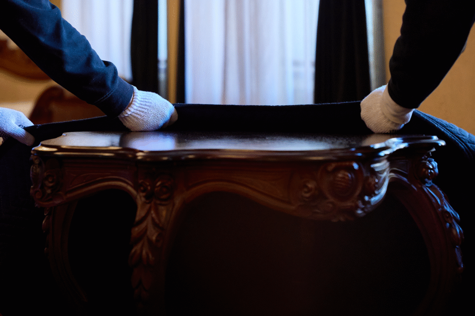 Nos déménageurs avec des gants qui recouvrent une table dans un déménagement.