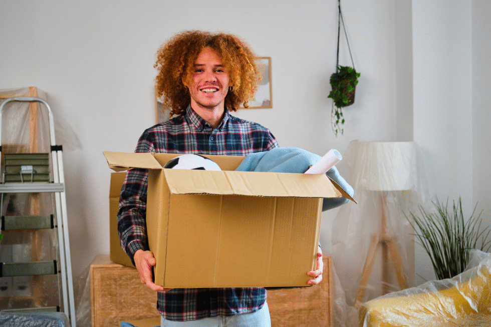 Un jeune homme ravi d'avoir aménagé dans son nouvel appartement après son déménagement.